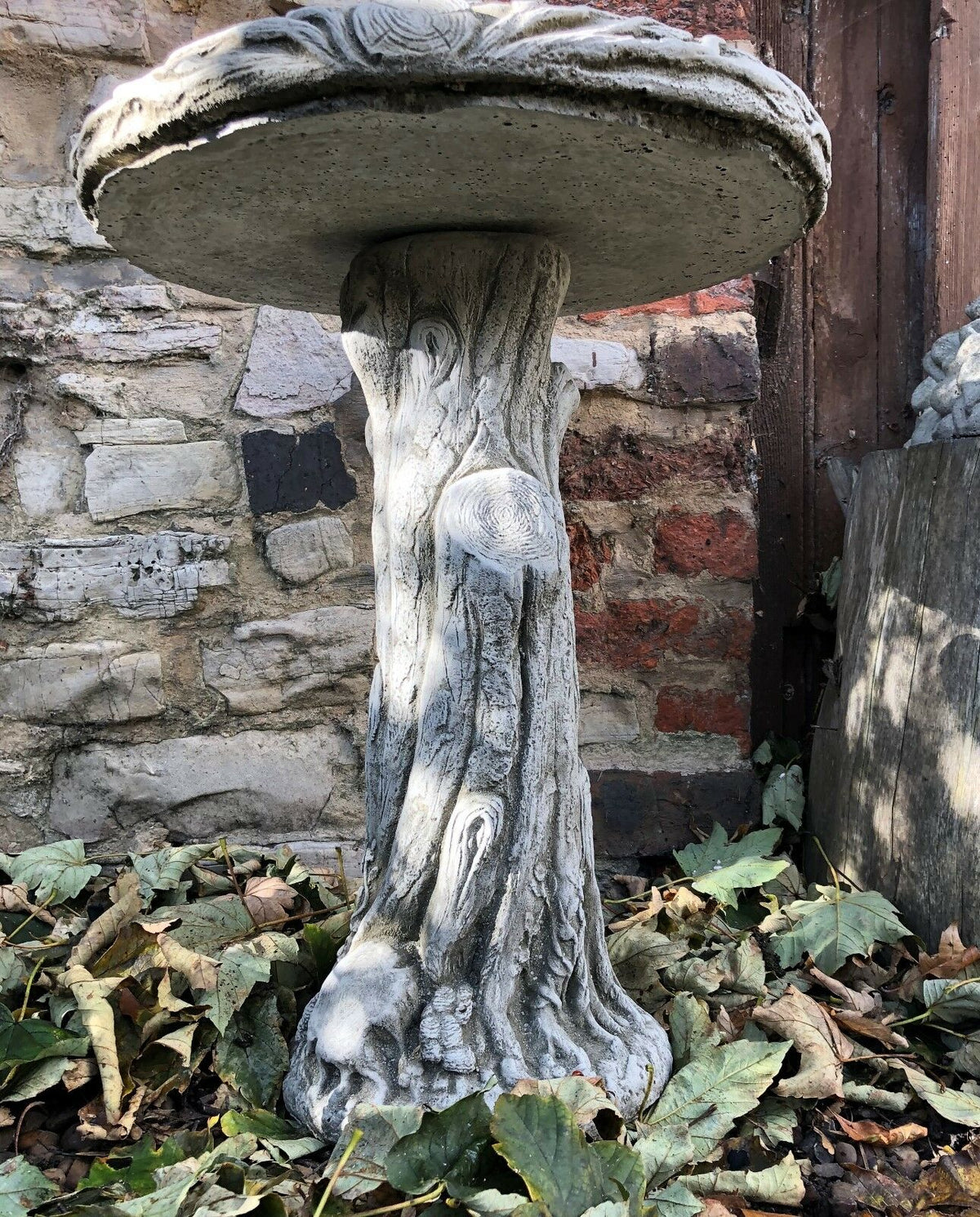 Underside view of stone bird bath with realistic tree trunk texture, ideal for rustic garden settings in the UK.