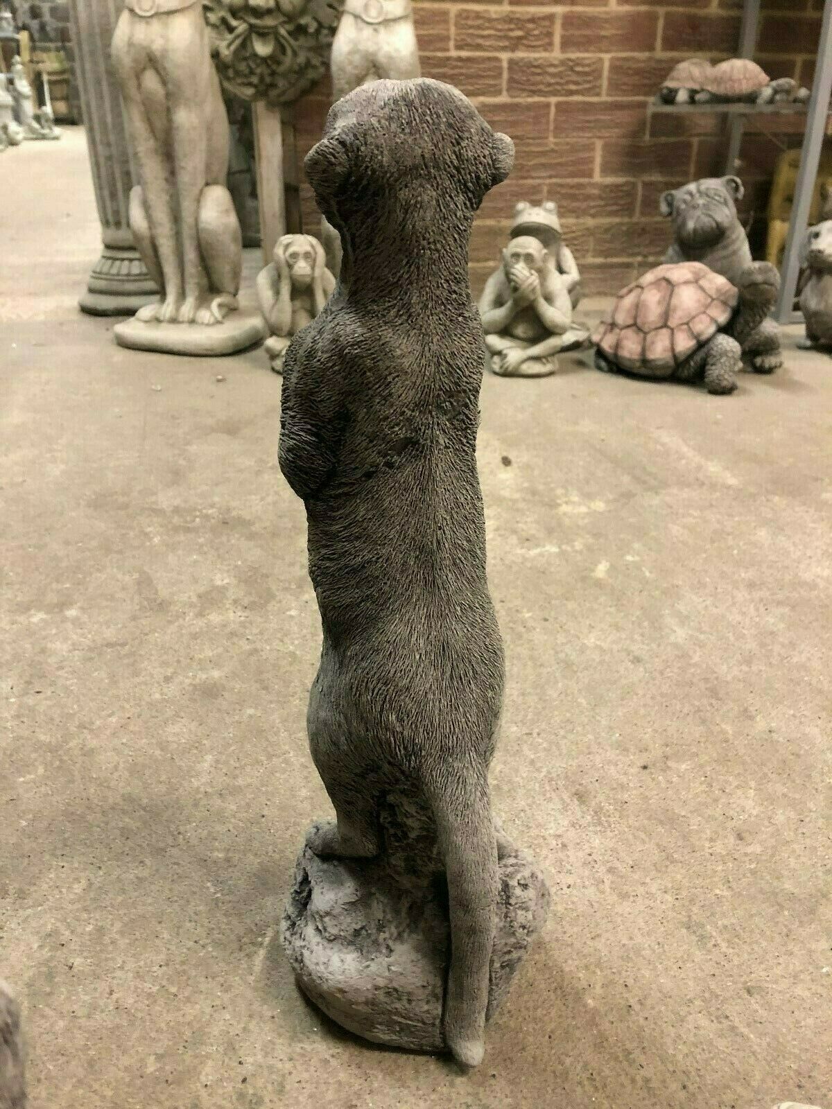 Back view of a standing stone meerkat statue, highlighting its textured finish and durability for garden use.
