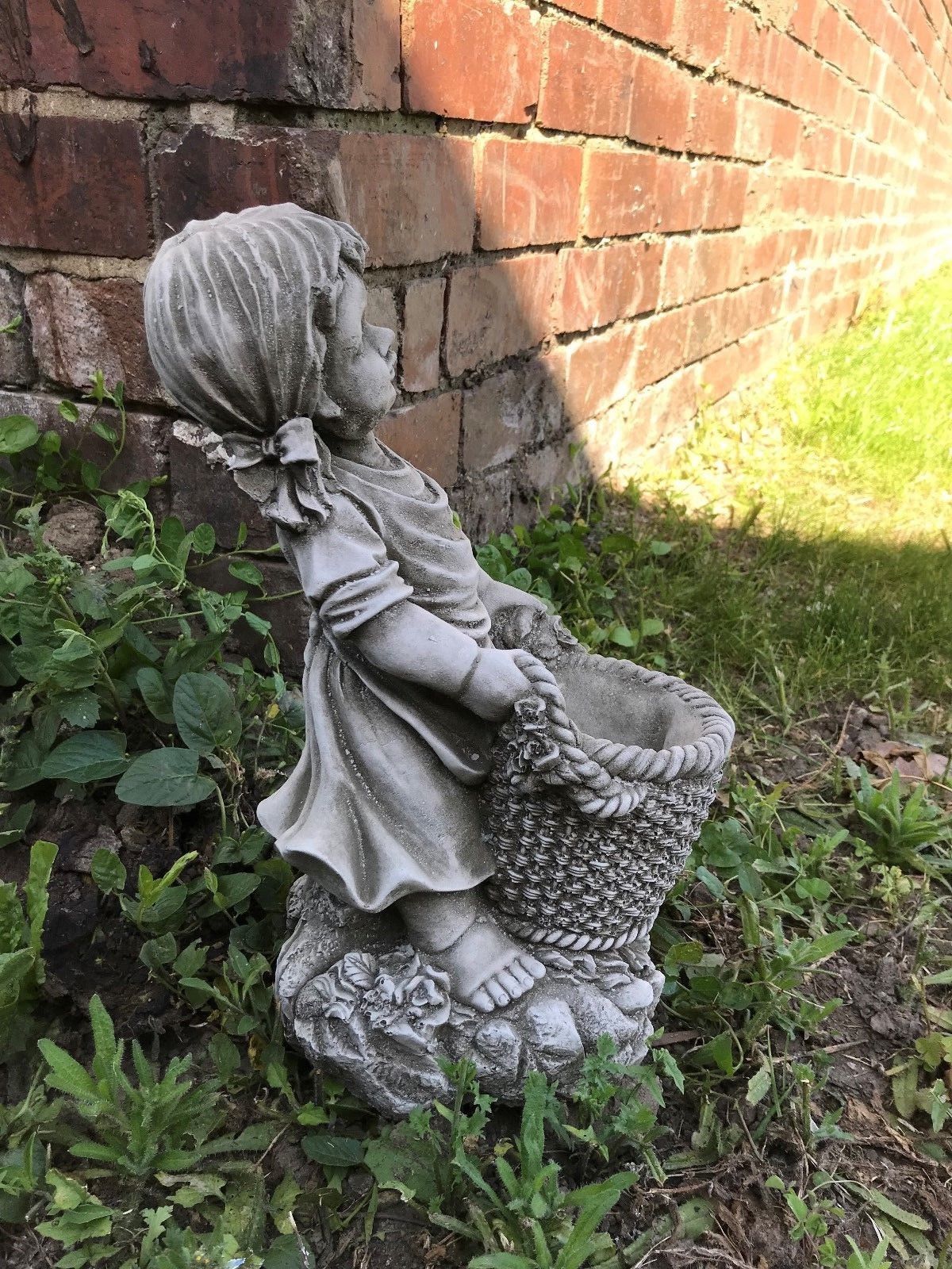 Profile view of the Stone Basket Girl Garden Planter Ornament with braided hair and floral base, enhancing garden aesthetics.