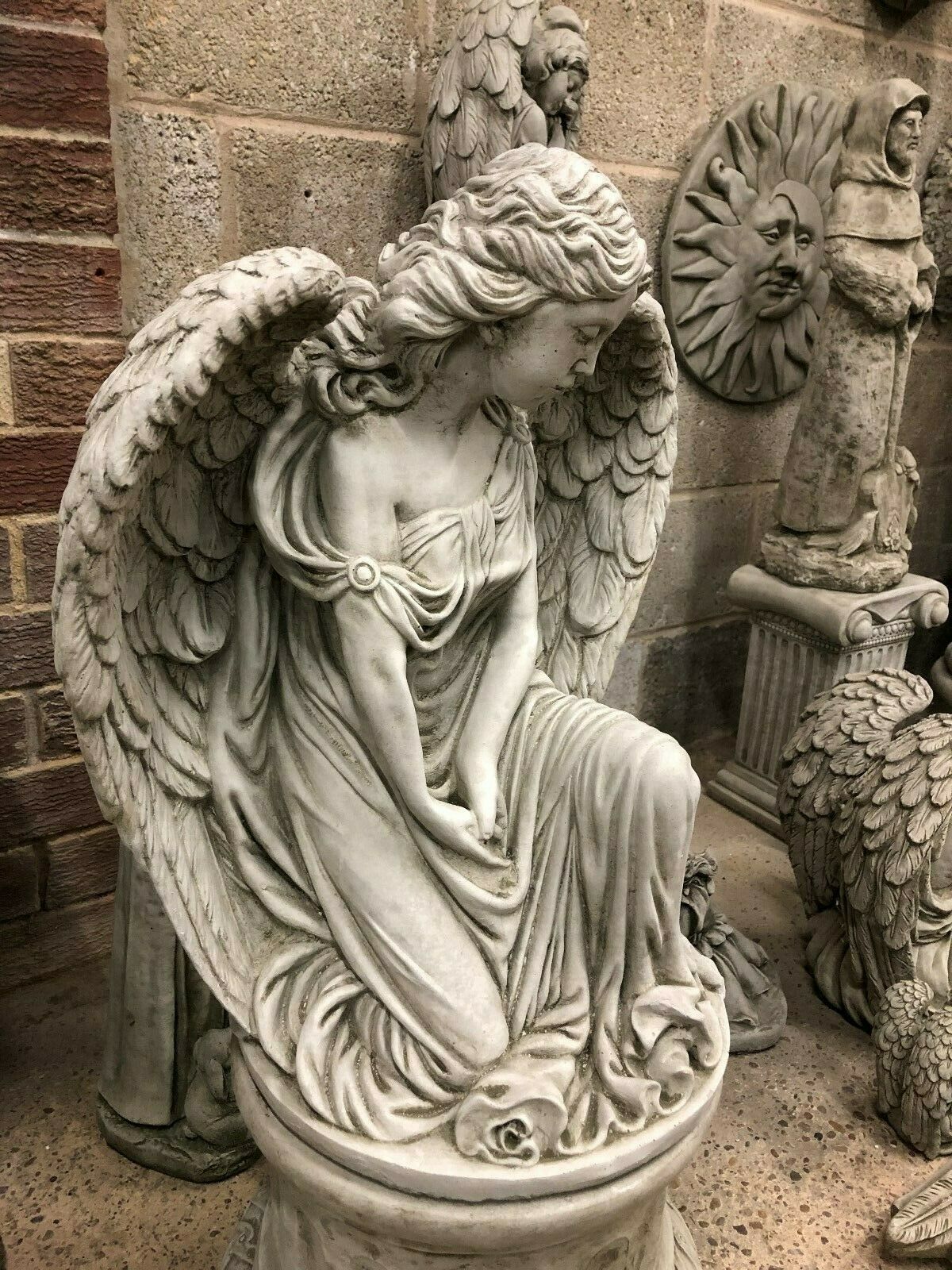 Close-up of Elegant Stone Angel Garden Pedestal Statue for Landscaping. Highlights the angel’s delicate facial features and flowing dress design.