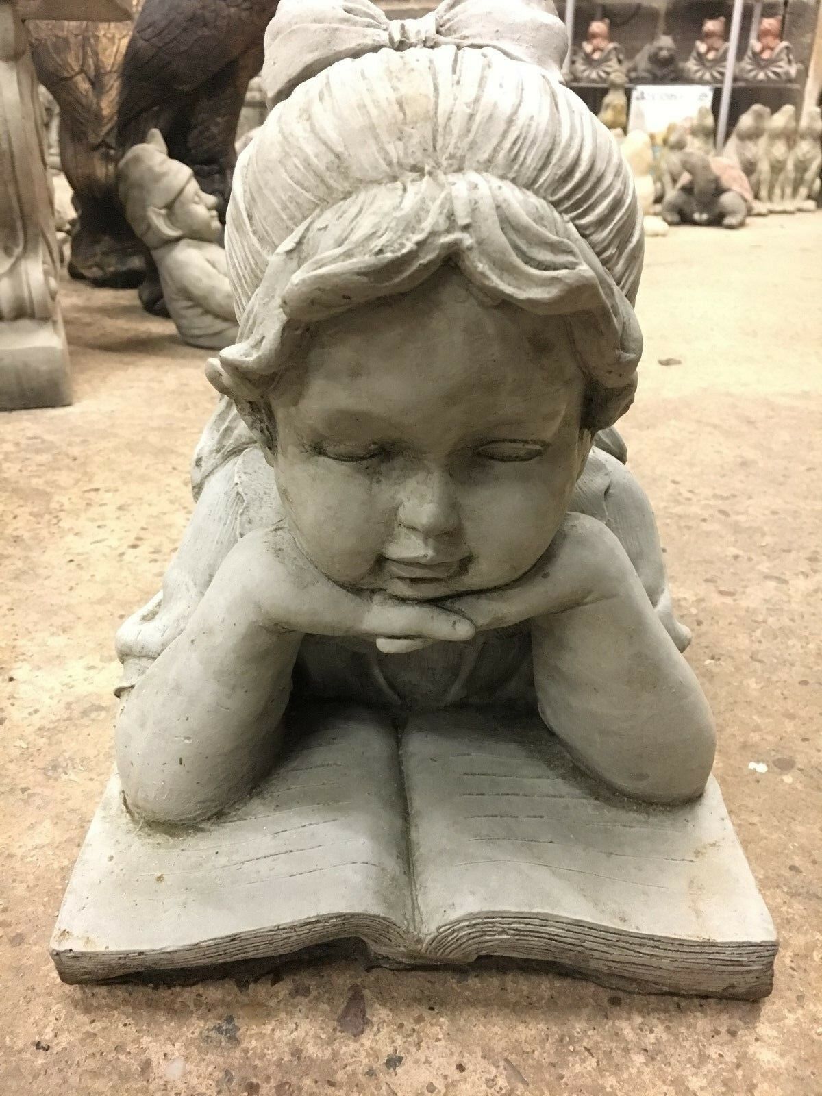 Front view of Reading Girl Statue with bow and book, crafted from durable stone for elegant garden ornamentation.