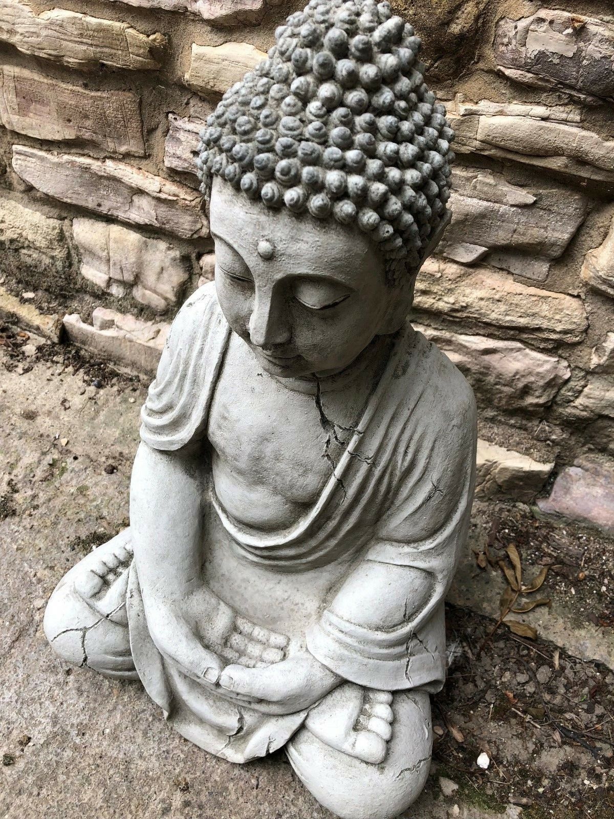 Top-down view of Buddha Statue in meditation pose, emphasizing hand detail and antique limestone texture for decorative garden use.