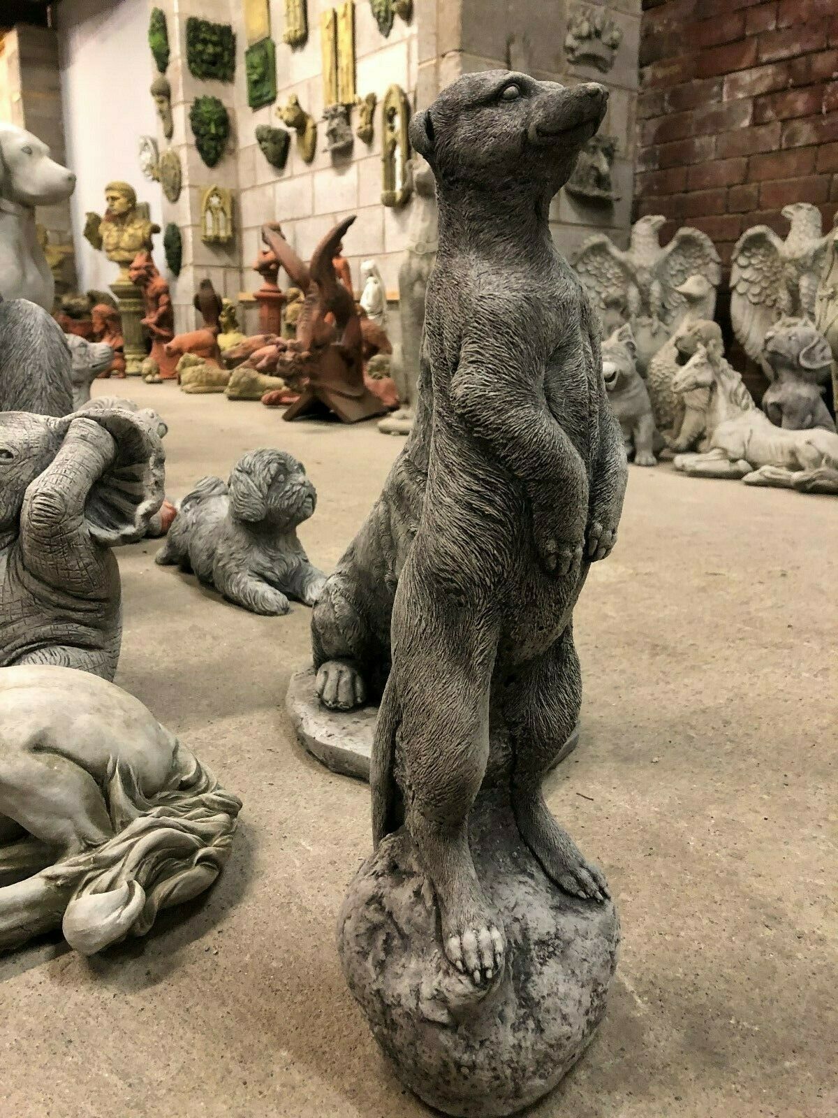 Angled view of a stone meerkat garden sculpture in a display room, ideal for enhancing garden aesthetics.