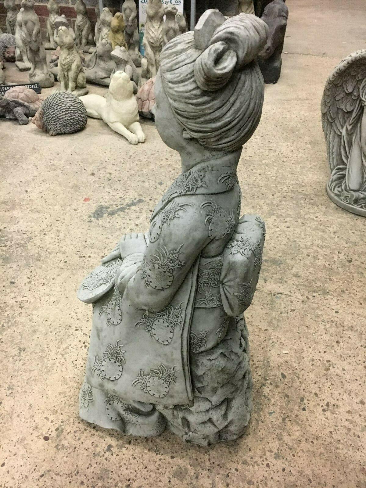 Side profile of Stone Kneeling Geisha Lady Statue with detailed obi and hair bun, a refined addition to patio or lawn decor.