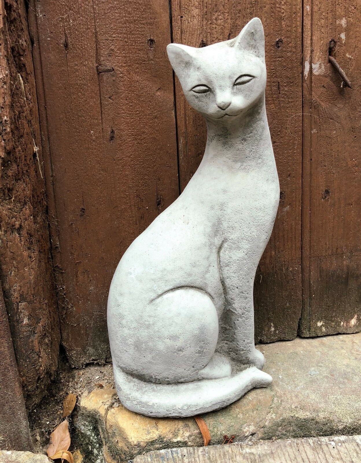 Left-facing stone Siamese cat statue with smooth finish and elegant form, perfect for outdoor garden decor.