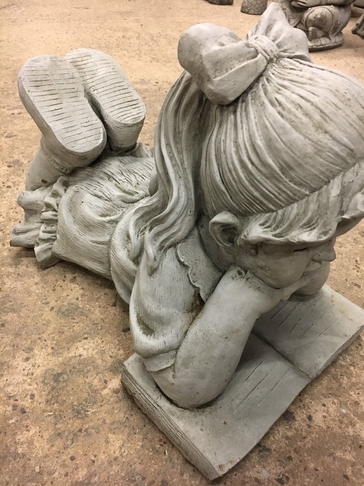 Angled view of Reading Girl Statue in limestone, showing detailed hair and dress, ideal for decorative garden settings.