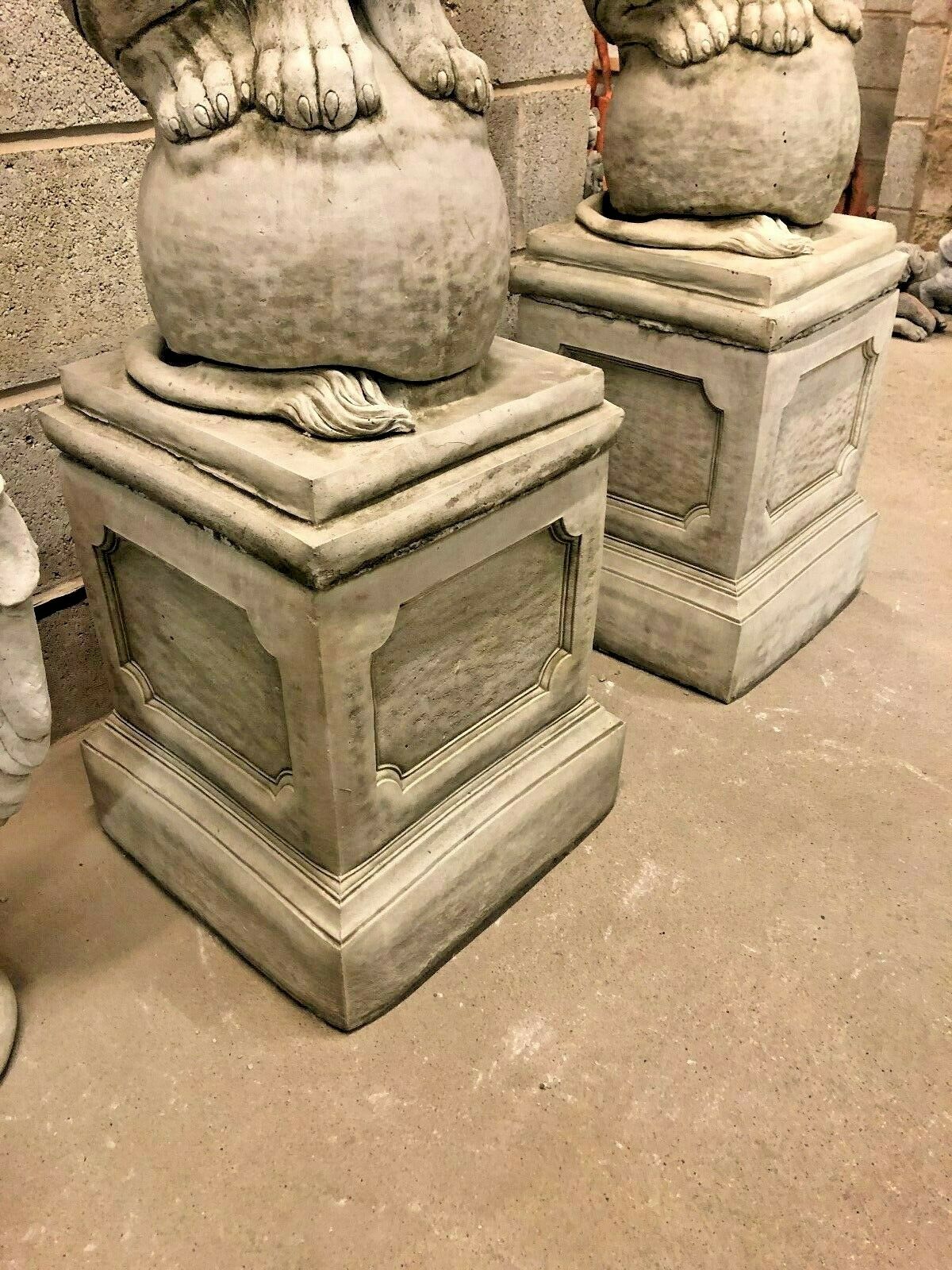 Lower view of lion statues on limestone plinths, emphasizing the solid and heavy base ideal for stable garden placement.