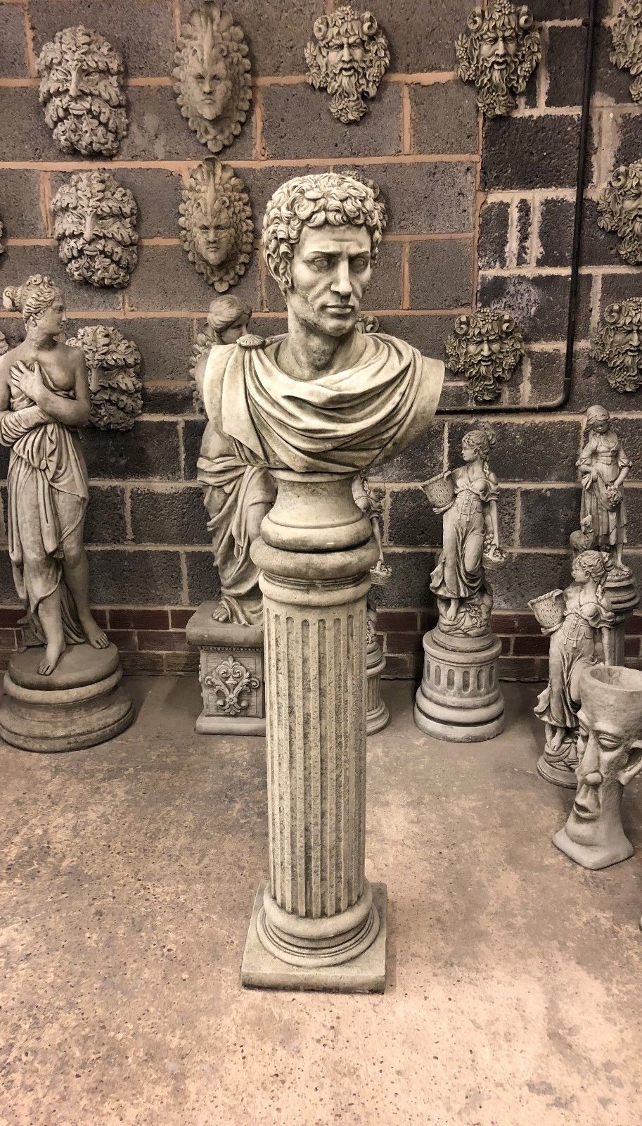 Front-facing Stone Marc Anthony Bust Statue on tall Roman plinth, crafted from solid limestone for classic garden ornament appeal.