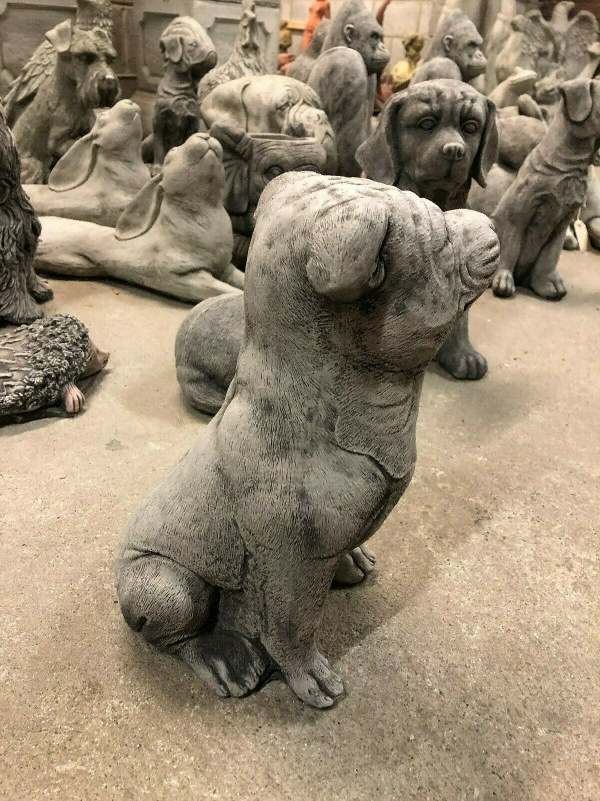 Stone Staffordshire Bull Terrier Statue for Garden Decor. Handmade stone sculpture of a seated bull terrier, ideal for patios or lawn ornamentation.