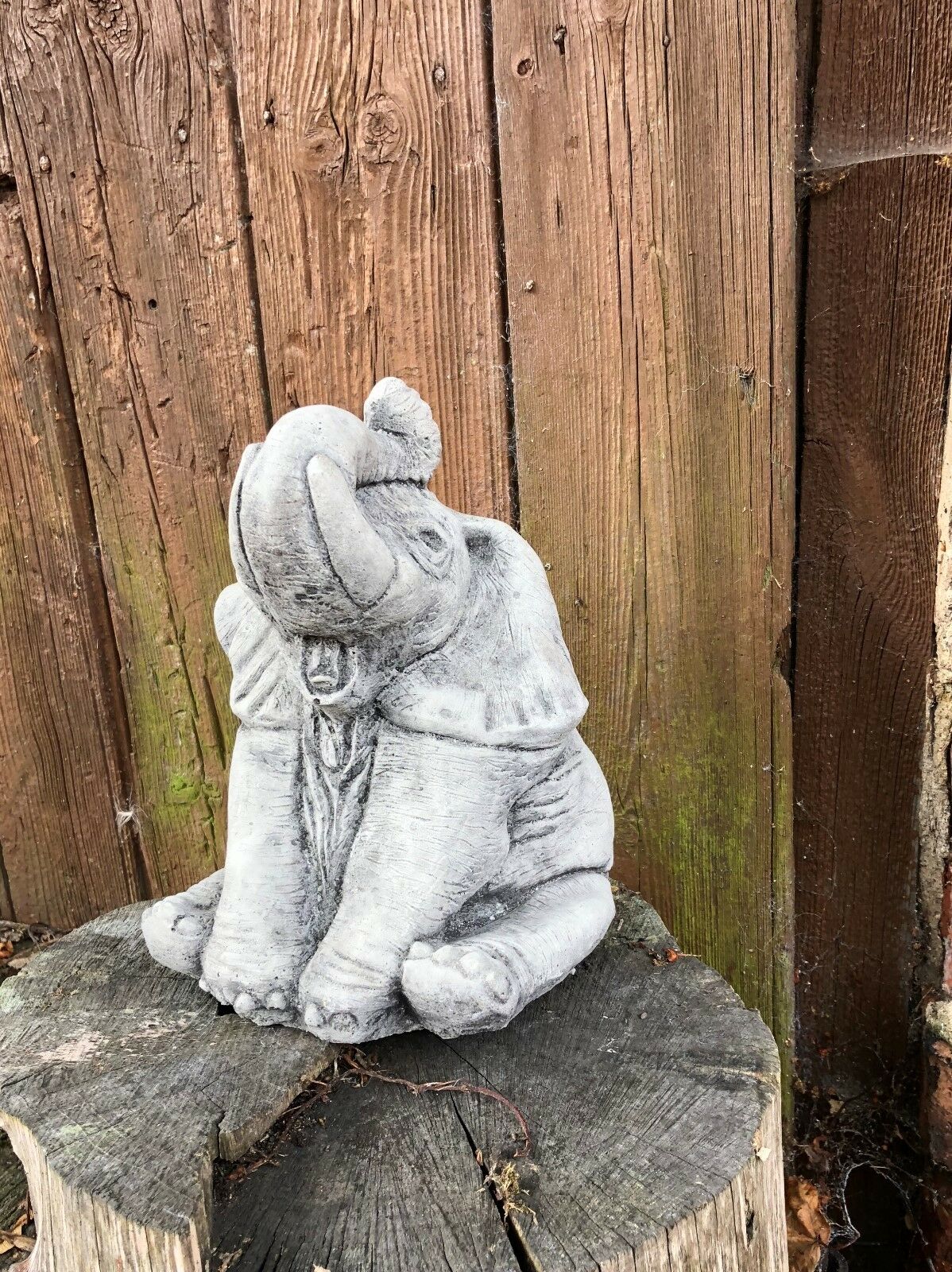 Detailed stone baby elephant statue with joyful expression, designed for outdoor garden decor or as a charming lawn sculpture.