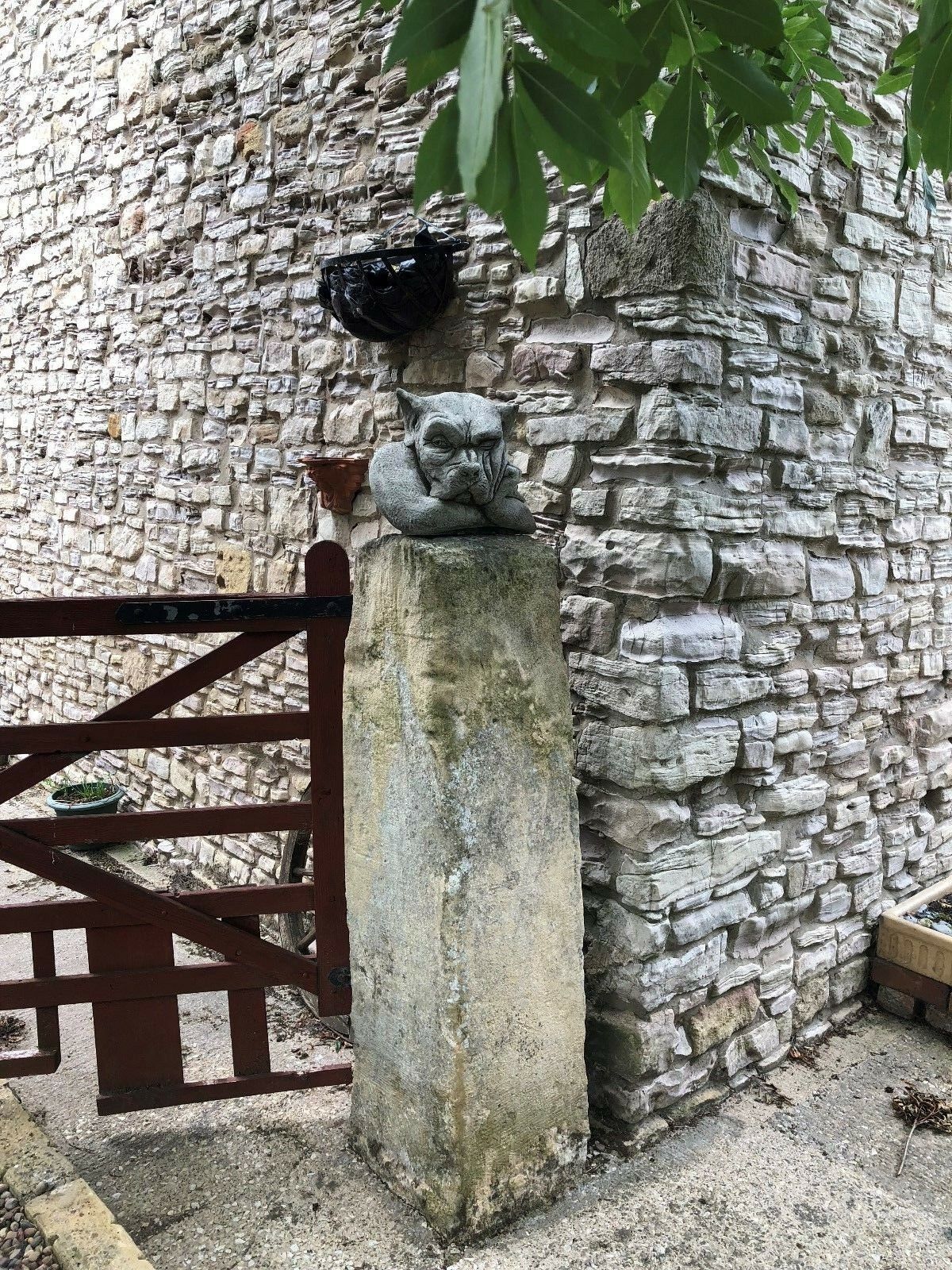 Full view of Gargoyle Dog Finial - Stone Garden Ornament mounted on a tall gate post, enhancing rustic garden aesthetics.