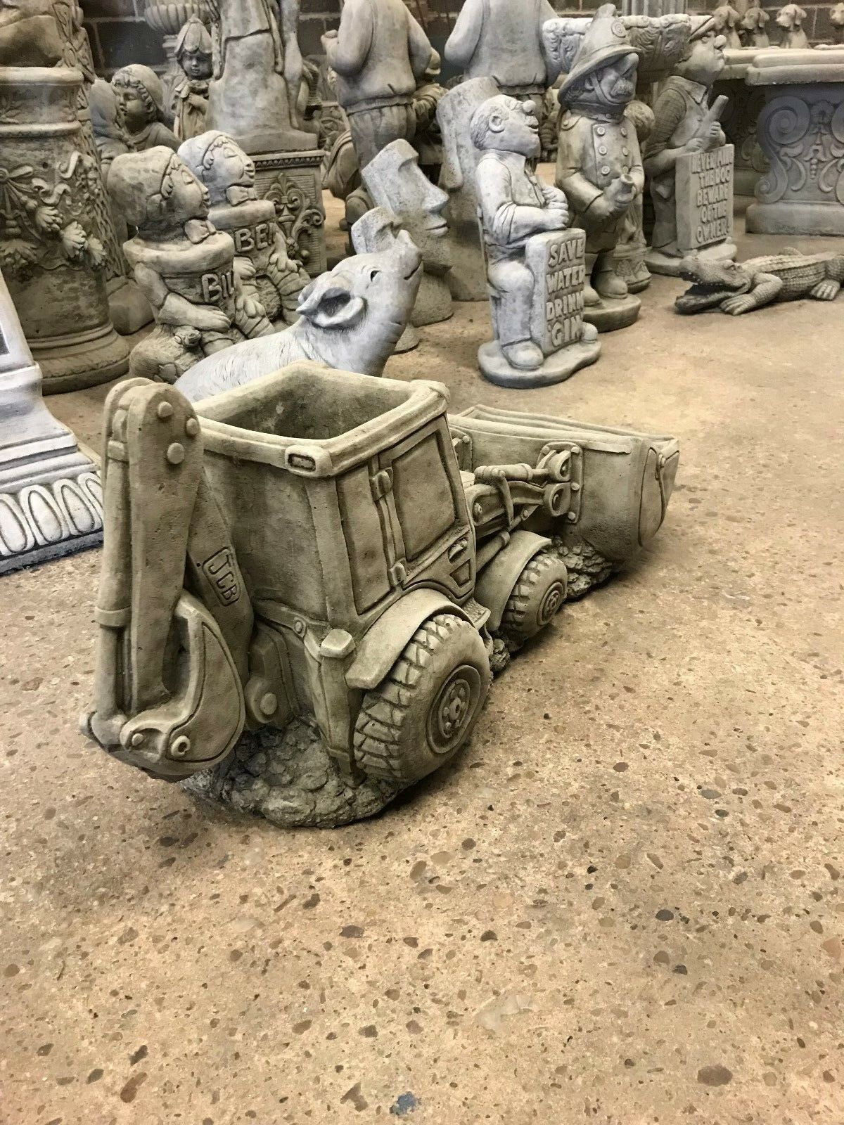 JCB Shovel Digger Planter - Garden Feature | Heavy & Durable handmade garden planter shaped like a digger, surrounded by decorative sculptures.