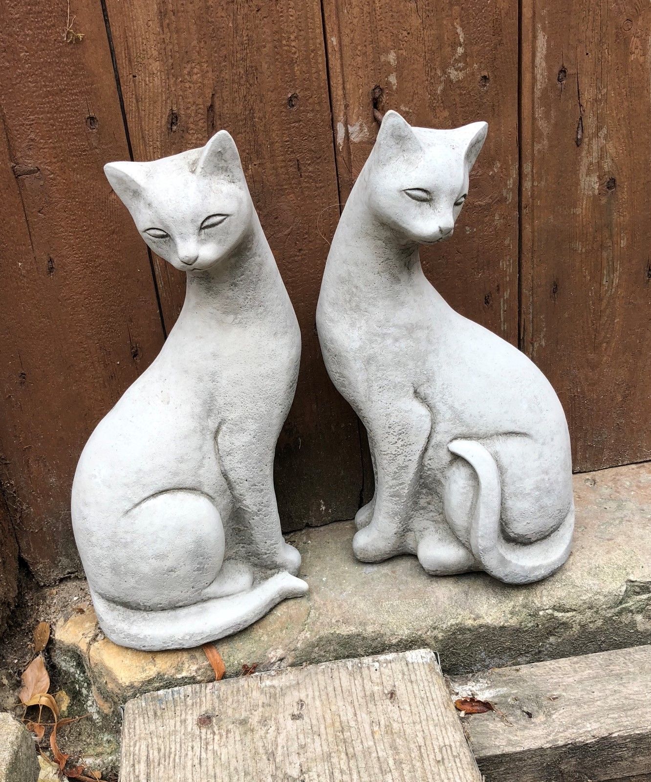 Elegant pair of stone Siamese cat statues posed together on a stone step, ideal for weatherproof garden decoration.
