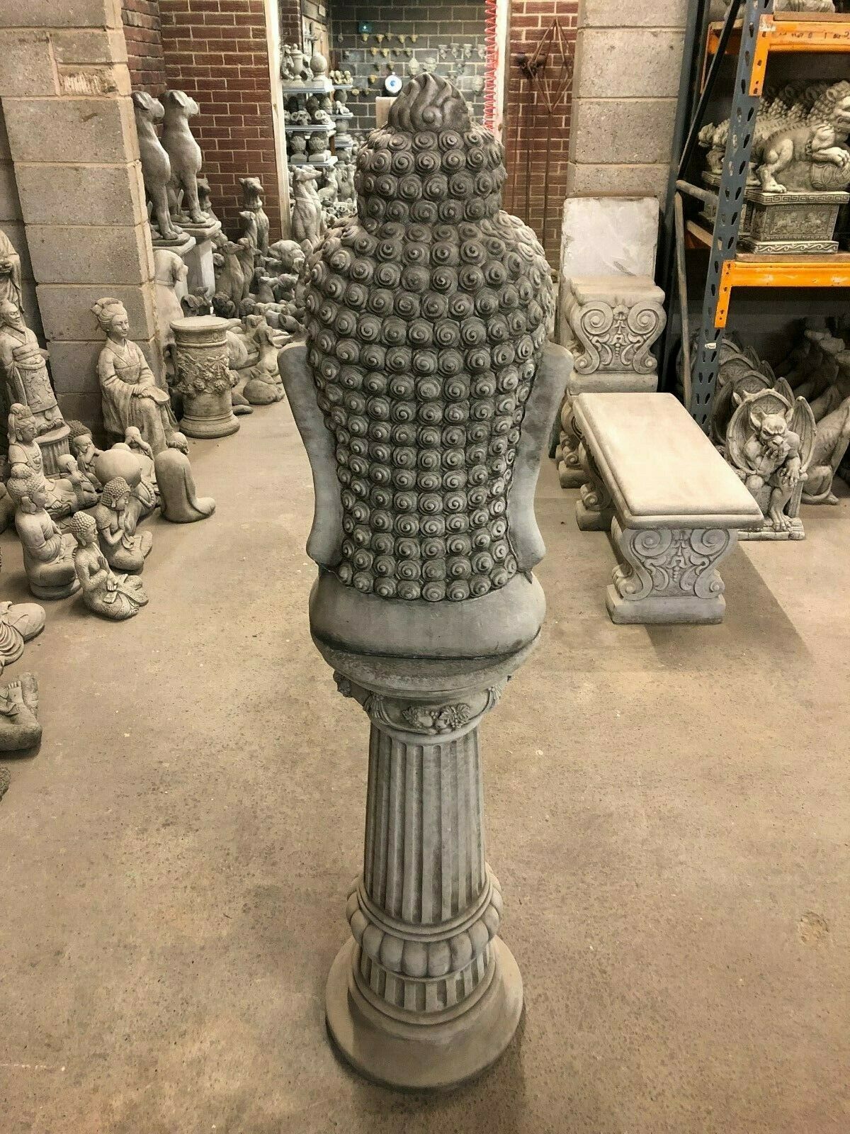 Back view of tall Buddha Head Garden Statue on decorative plinth. Elegant and durable garden sculpture for outdoor display.