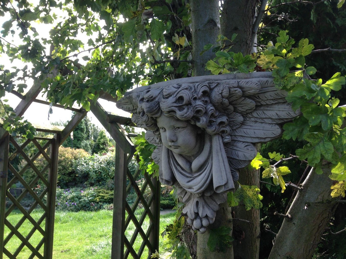 Side view of Stone Cherub Garden Wall Shelf showing detailed wings and curly hair, perfect for garden decor. Made from solid limestone for long-lasting use.