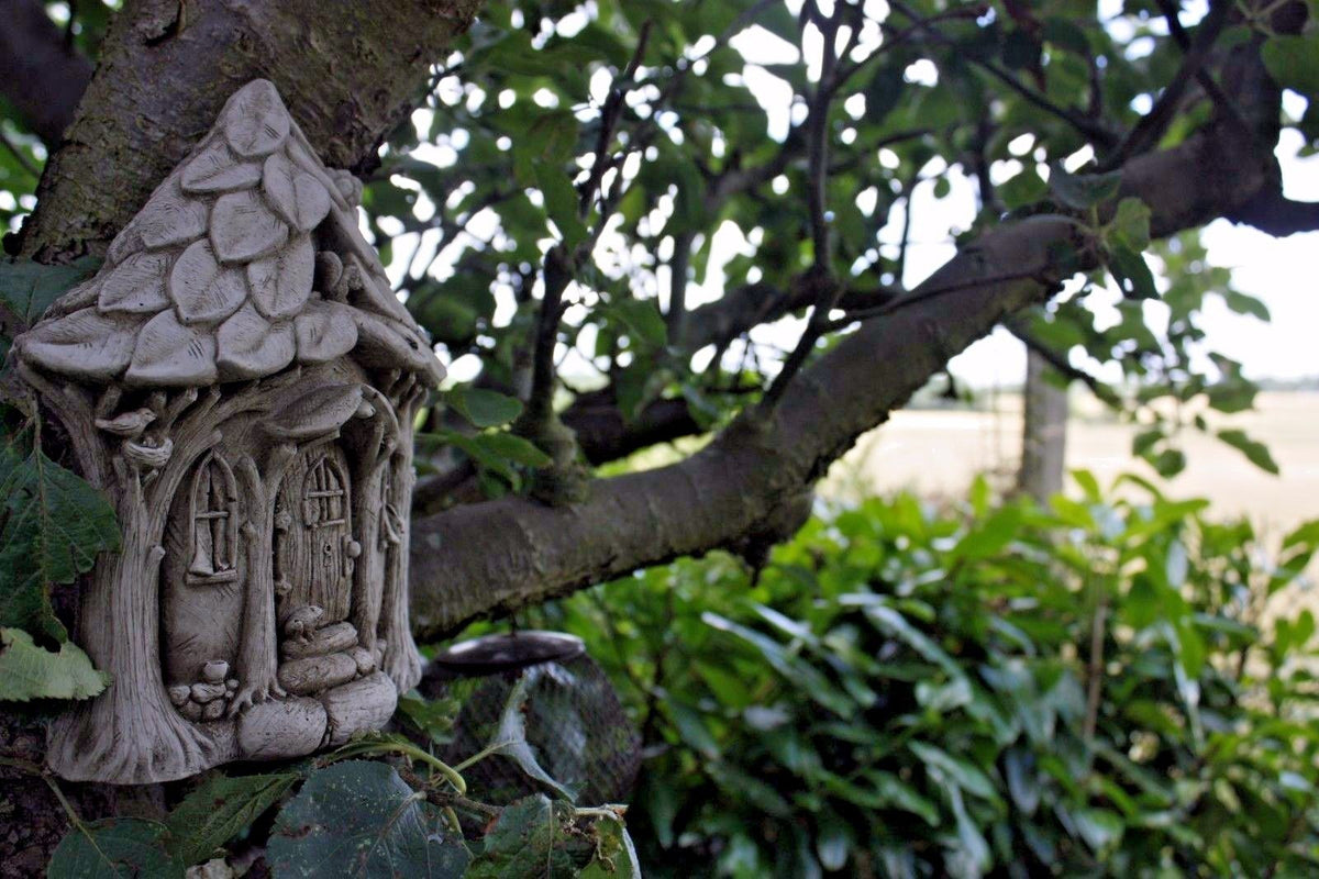 Stone Fairy Garden House wall plaque mounted on a tree, surrounded by lush greenery. Ideal for outdoor garden decor with a magical woodland theme.
