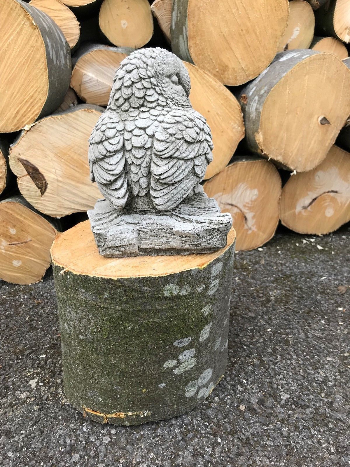Back view of baby owl garden ornament on log. Handcrafted limestone sculpture for outdoor animal-themed decor.