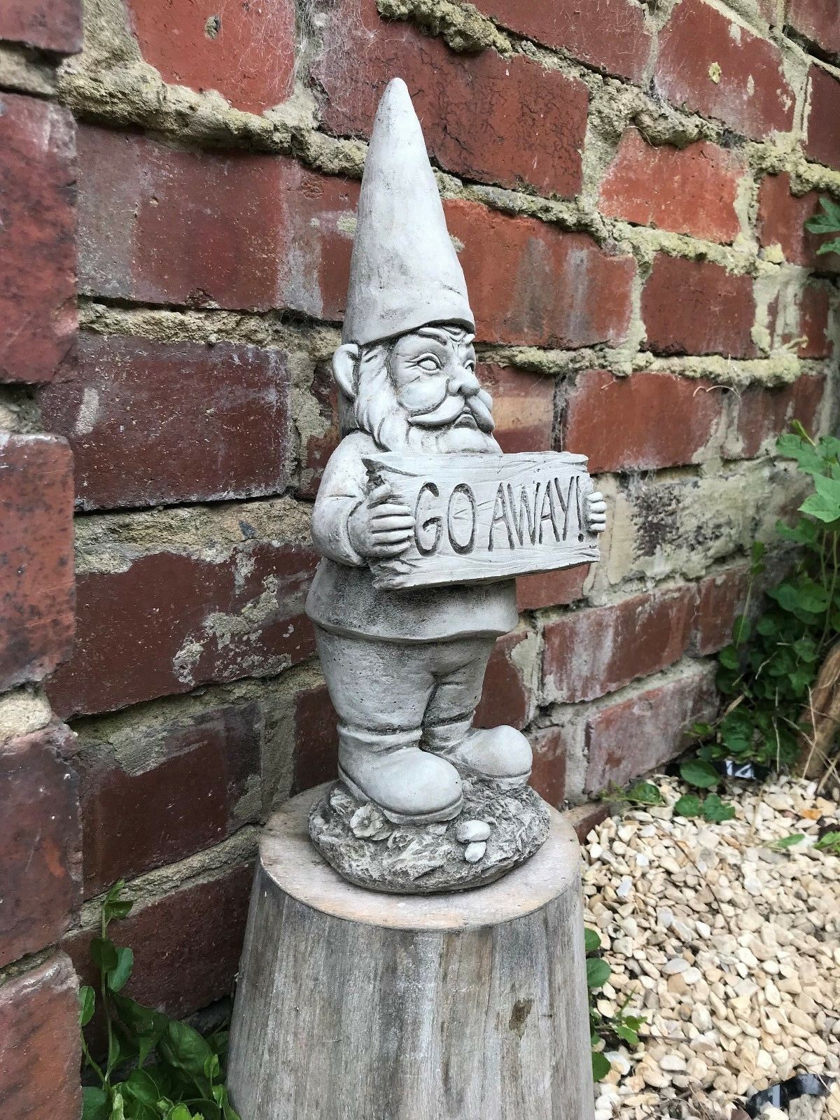 Angled view of the Grumpy Garden Gnome 'Go Away' statue, ideal for patios or flowerbeds, crafted from solid limestone.