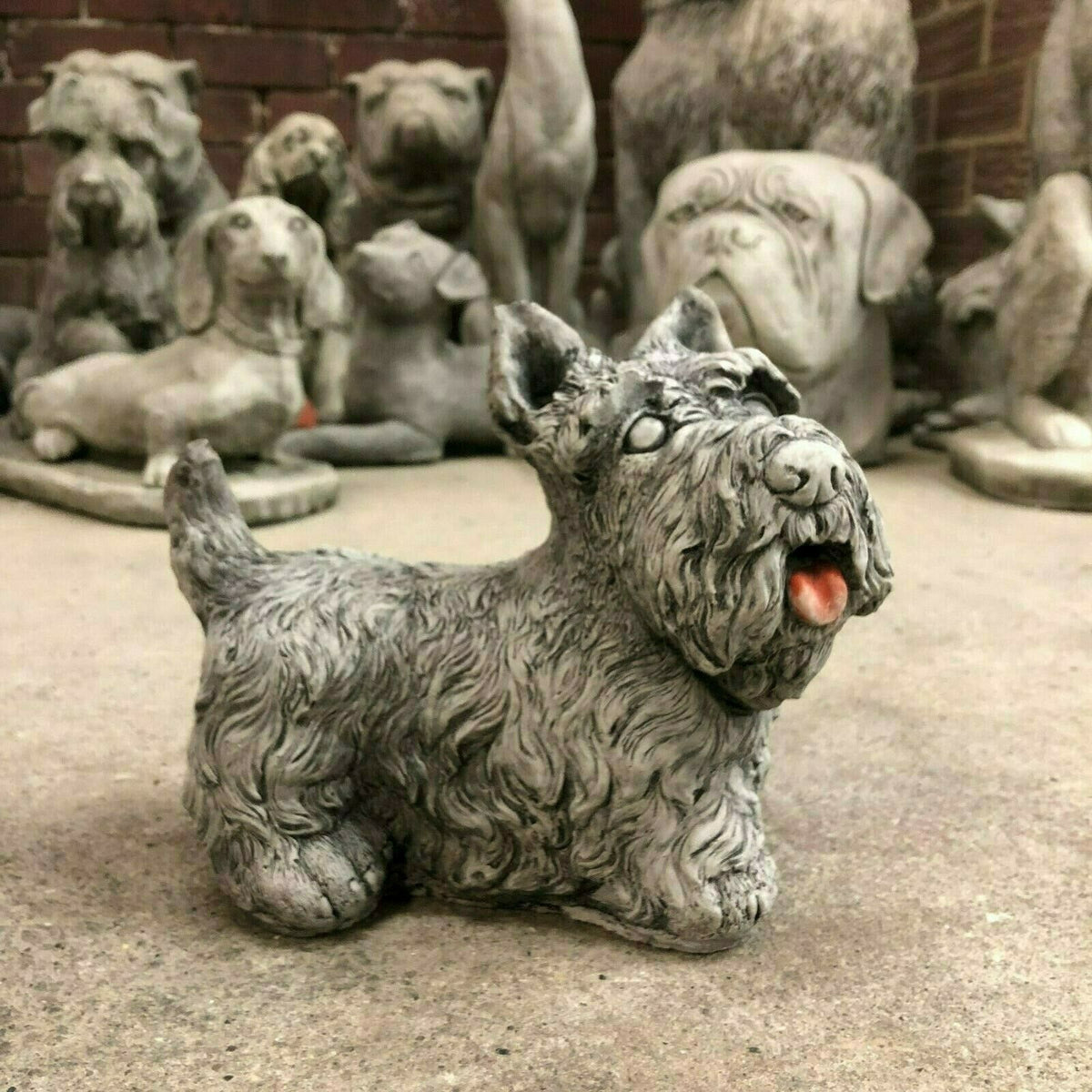 Stone Scottish Terrier garden ornament in antique grey, surrounded by other dog statues, perfect for patios or flowerbeds.