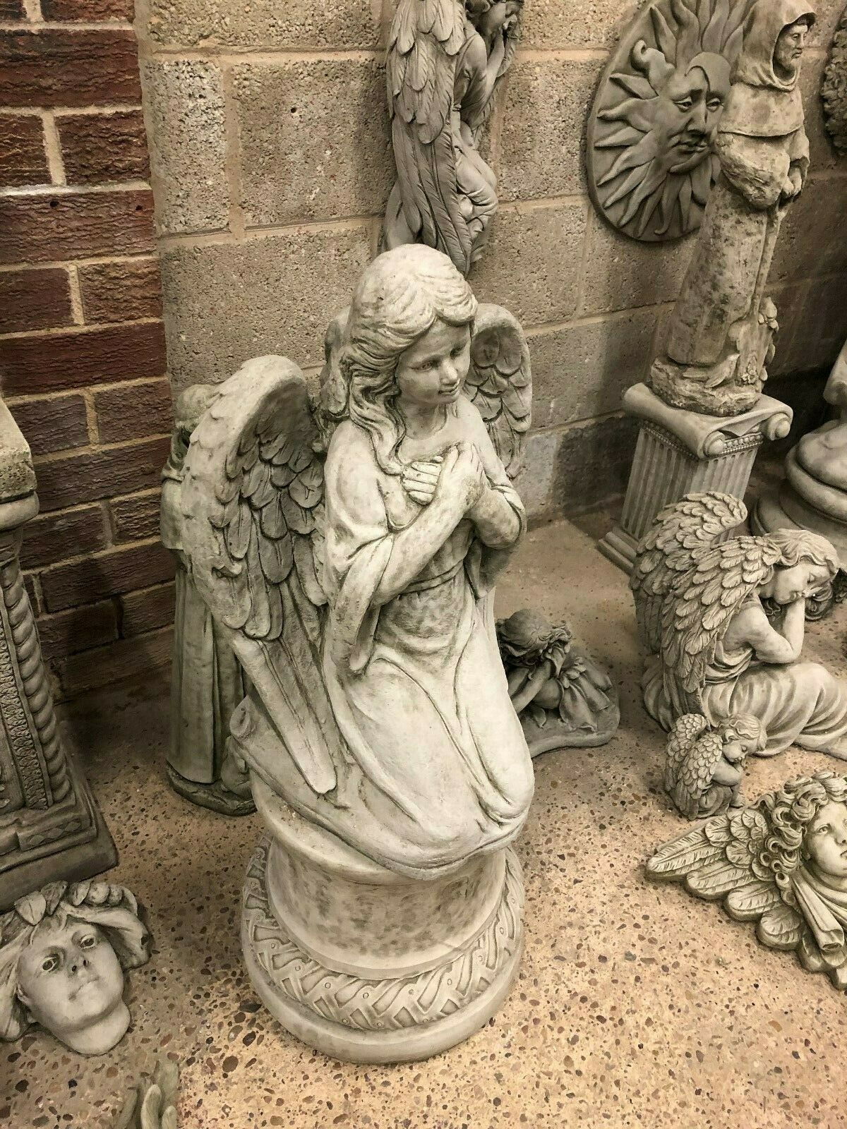 Handcrafted limestone angel statue in a prayer pose on a decorative plinth, suitable for flower beds or lawn ornamentation.